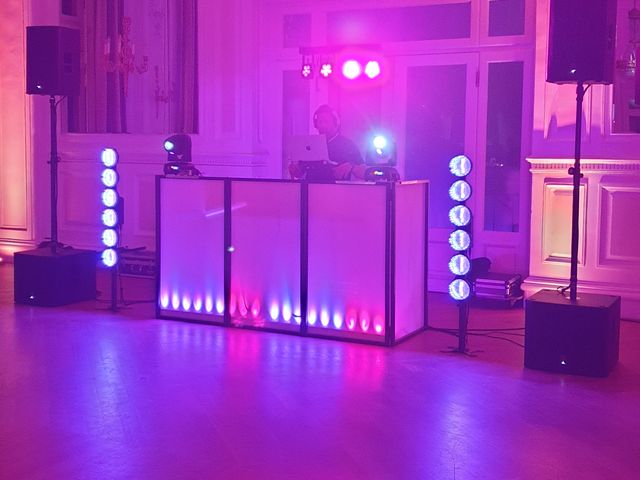 DJ pult z roza in modro osvetlitvijo v dvorani z balkonom