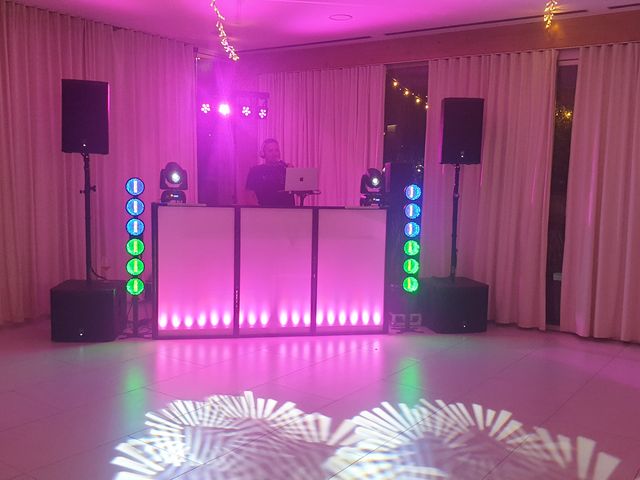 DJ pult z roza osvetlitvijo, svetlobnimi stebri in projekcijo vzorcev na tleh