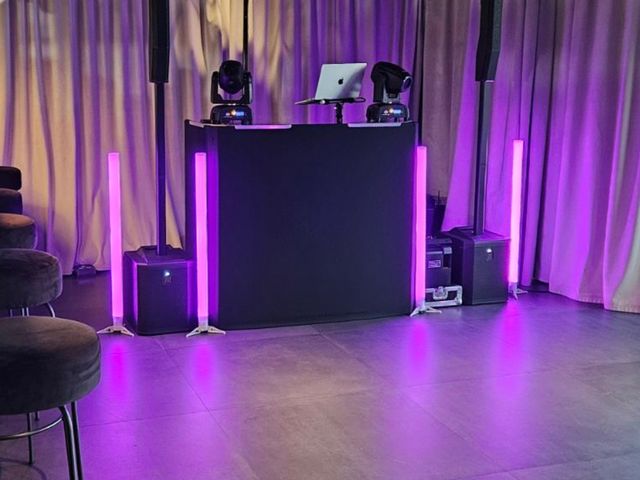 DJ pult s stebri in svetlobnimi palicami ob zavesah